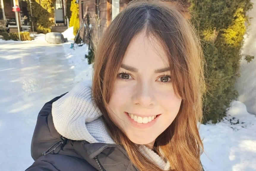 Une jeune femme devant une maison couverte de neige