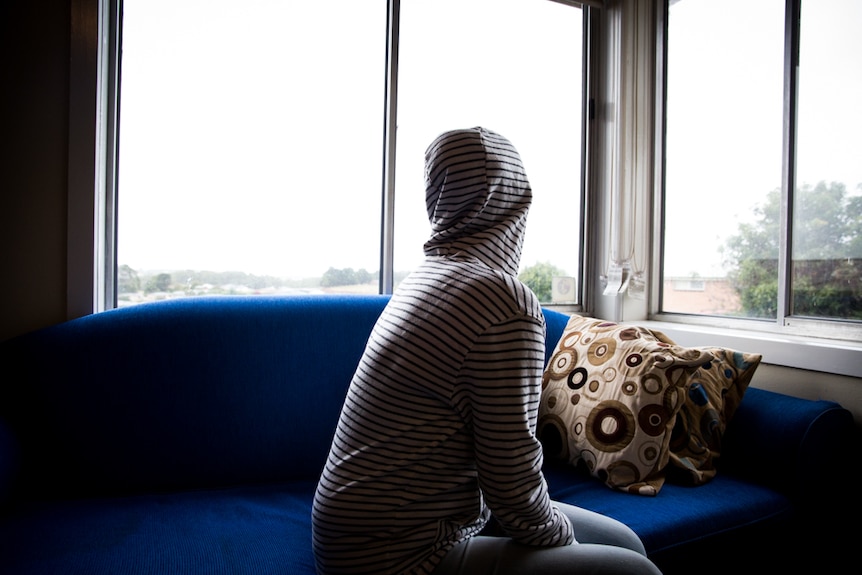 Mary sits on a couch in Burnie, regional Tasmania