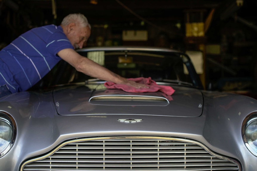 A man cleaning his Aston Martin car.