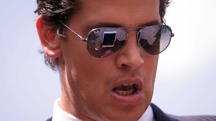 Milo Yiannopoulos looks at a tablet device during a press conference