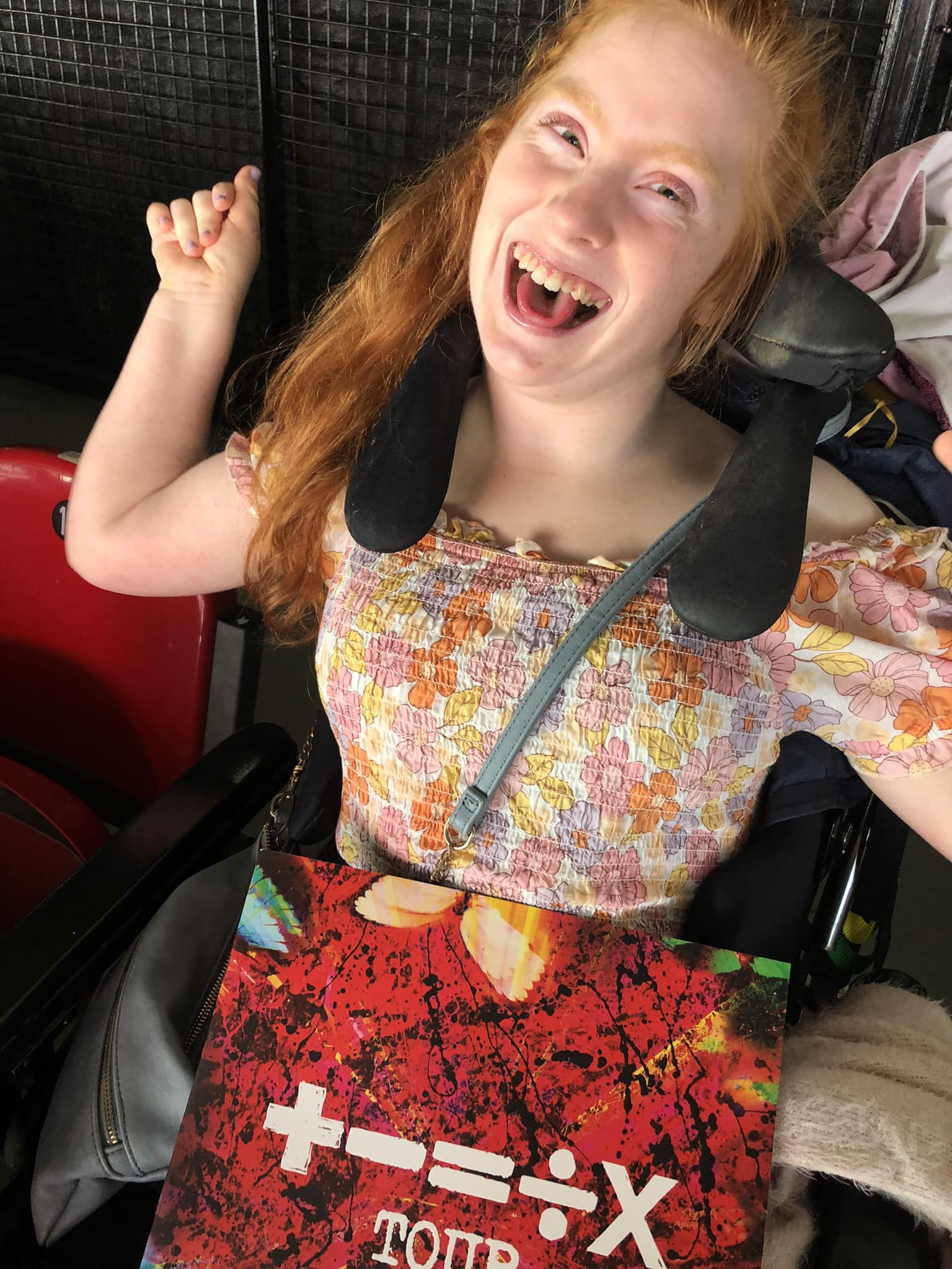 Kiah Haysom smiles widely at the camera, with the neck support of her wheelchair in shot.