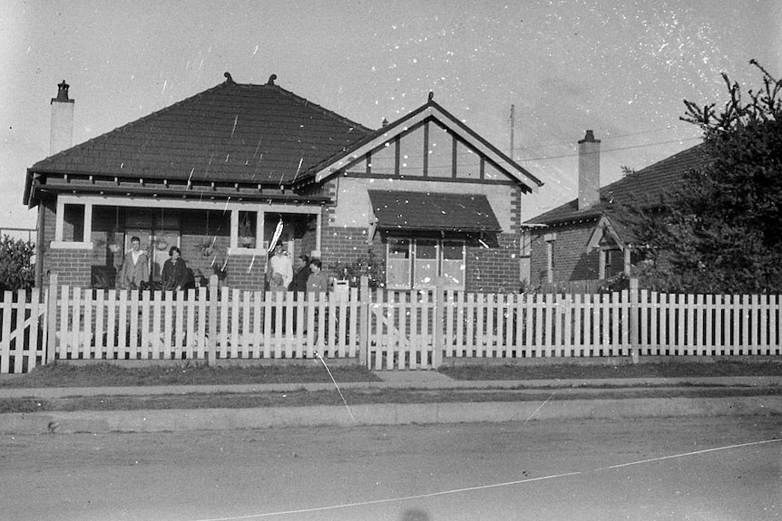 An undated photo of a suburban house with a picket fence. 