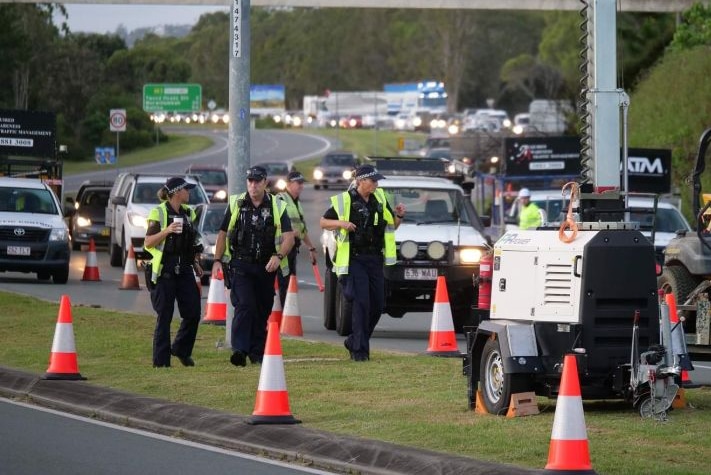 Police walk alongside traffic on a Queensland highway.