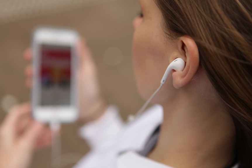 A woman listens to music through ear buds