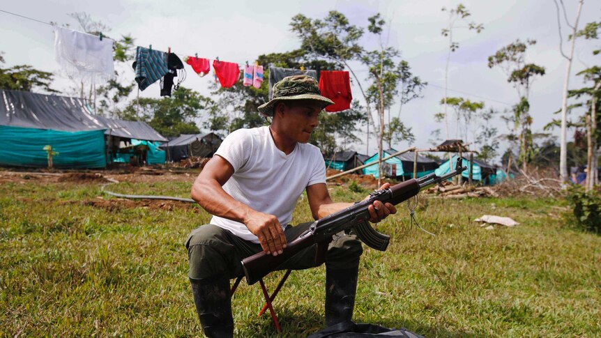 FARC rebel cleans his weapon at a camp in La Carmelita, Colombia.