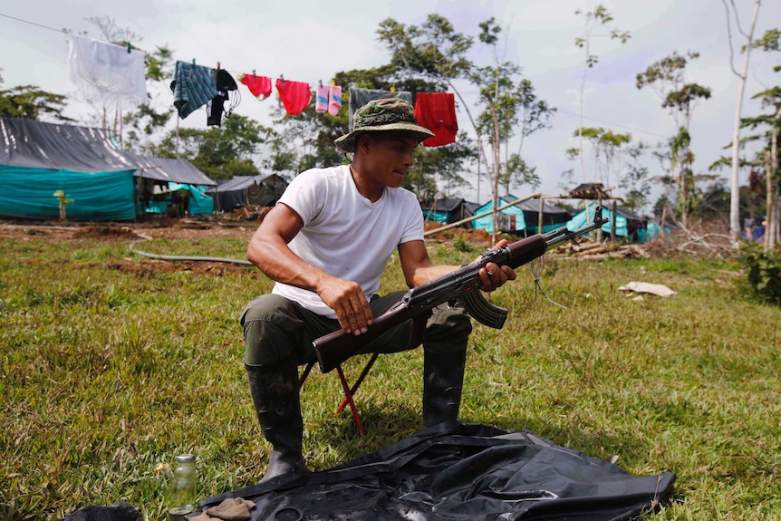 FARC rebel cleans his weapon at a camp in La Carmelita, Colombia.
