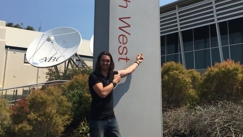 Musician Jonny Taylor pointing at the sign of ABC South West