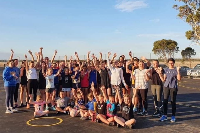 Members of the netball club raise their hands in joy on the newly resurfaced courts.
