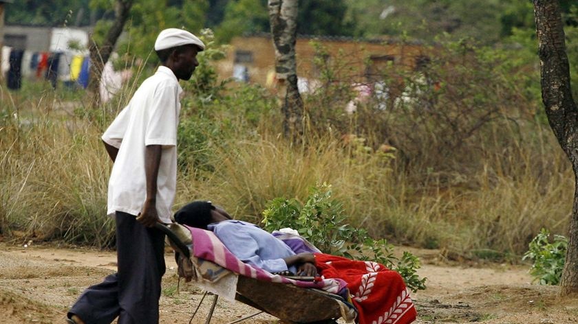 A man pushes his relative in a wheelbarrow to a Cholera Polyclinic in Harare