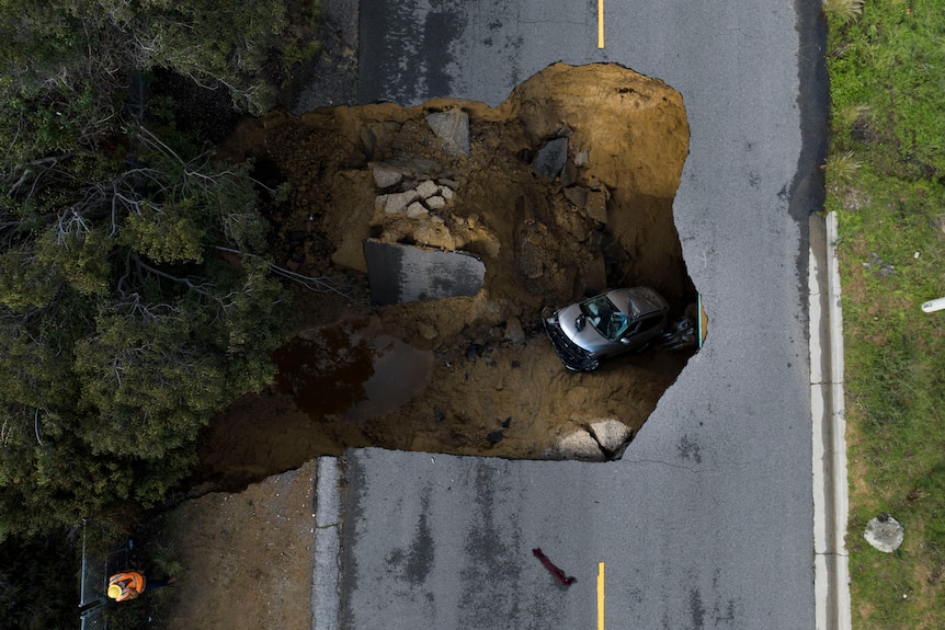 A drone shot of a large sink hole with cars inside