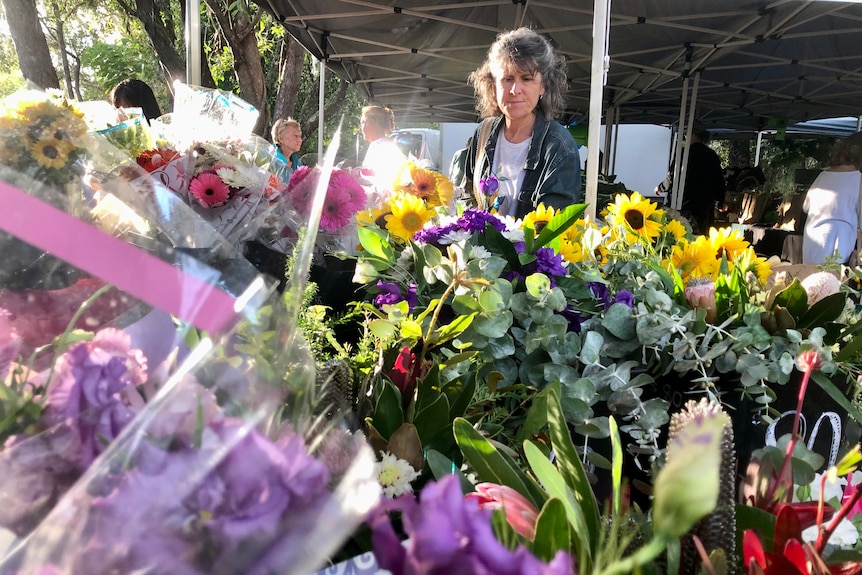 Bunches of flowers in the foreground and a customer looking over them in the background