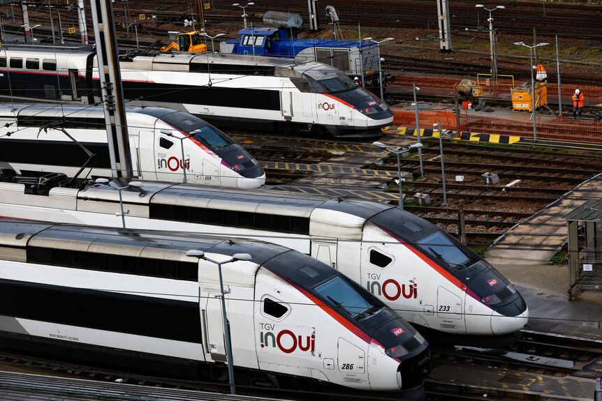 Four parked white, red and blue high speed trains are pictured in Paris. On the side it says 'TGV, inOui'. 