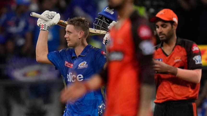 Australian cricketer Cam Green raises his bat in celebration after bringing up his hundred and winning an IPL game for his team.