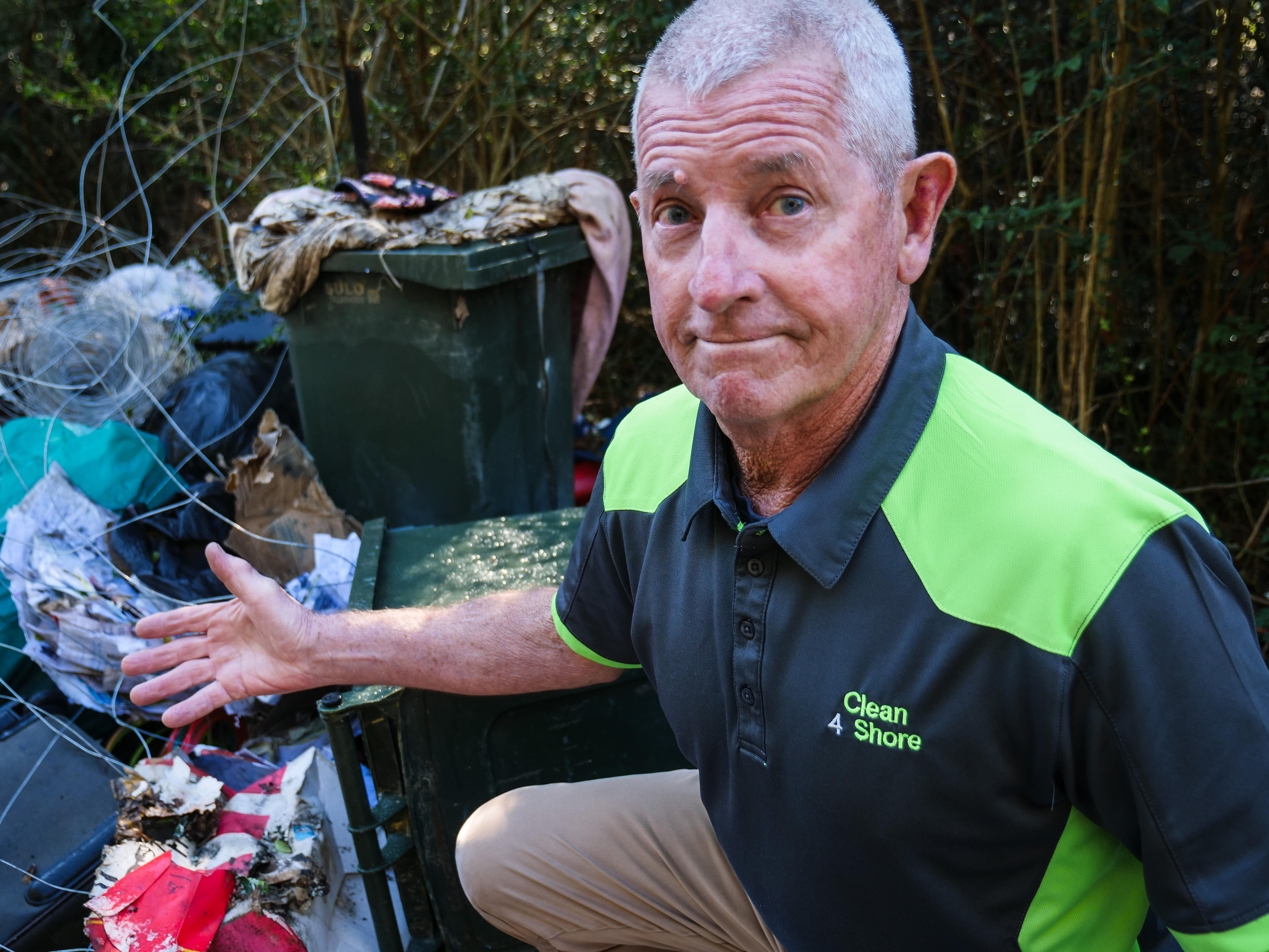 A man pointing to rubbish while looking at the camera.