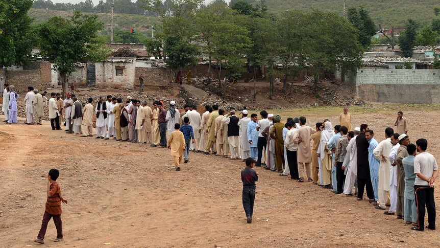 Hundreds of people wait to vote on the outskirts of Islamabad.