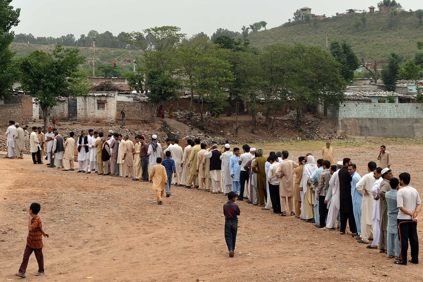 Hundreds of people wait to vote on the outskirts of Islamabad.