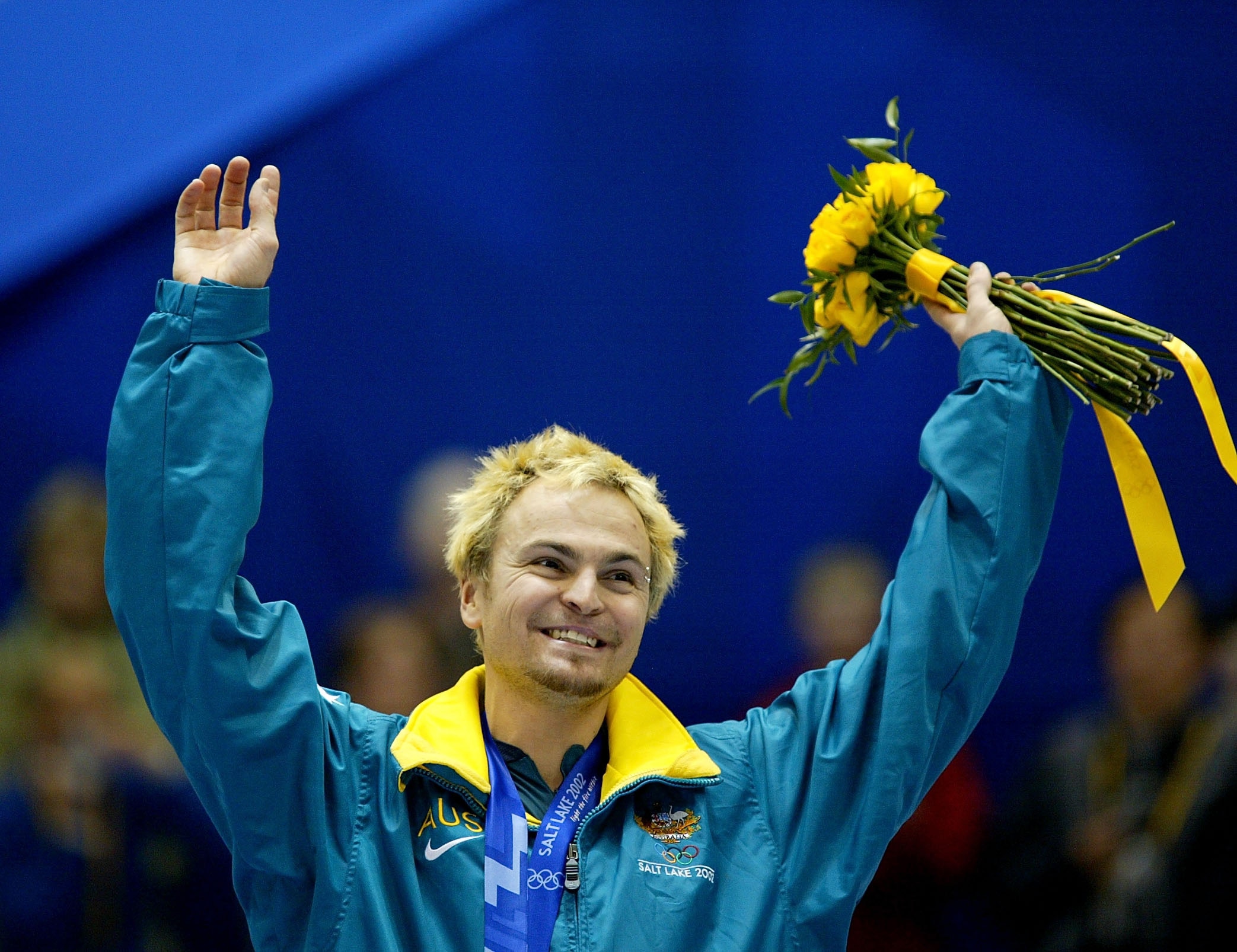 Steven Bradbury sobe em um pódio e acena com as mãos