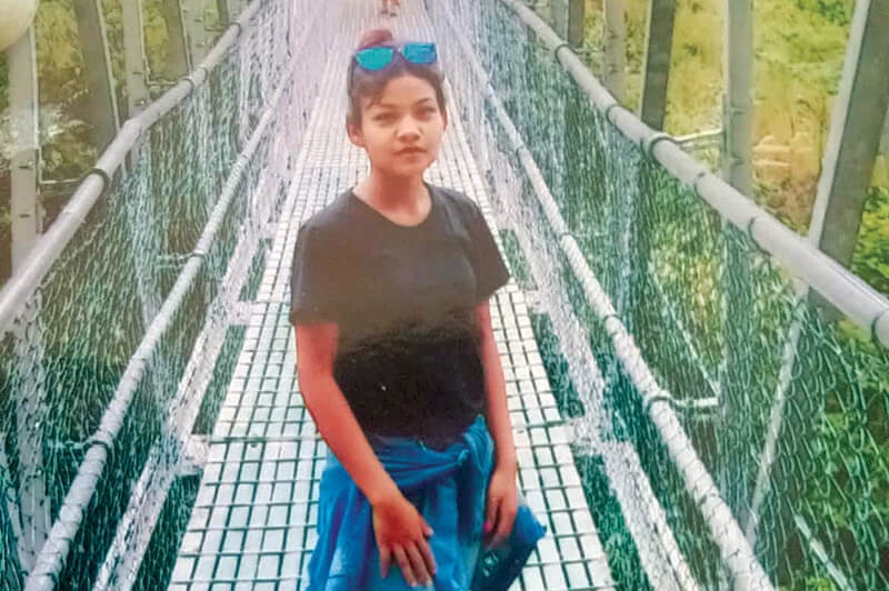 An image of a teenager standing on a wooden bridge