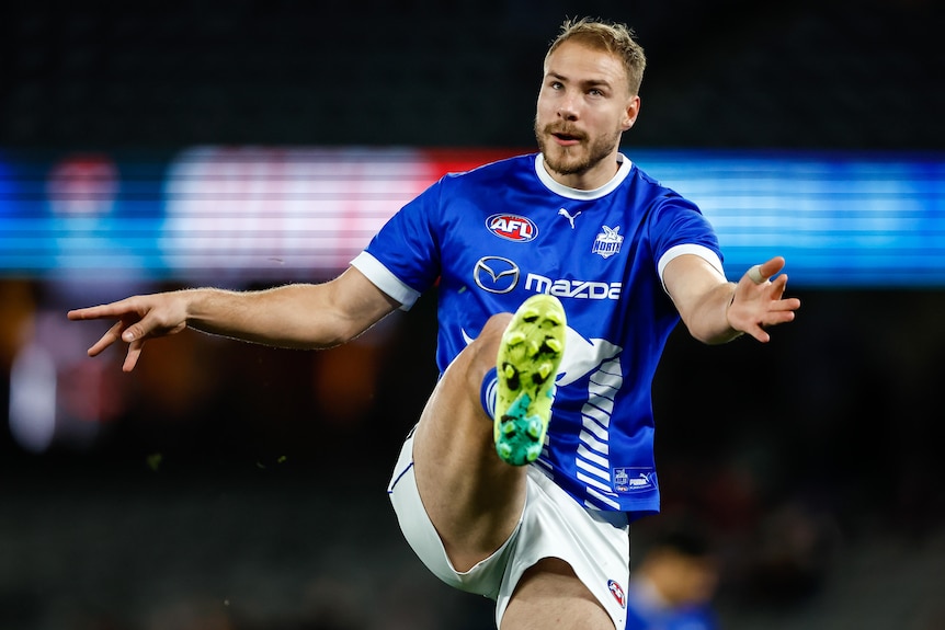 Ben McKay kicks a footy while wearing North Melbourne's training shirt