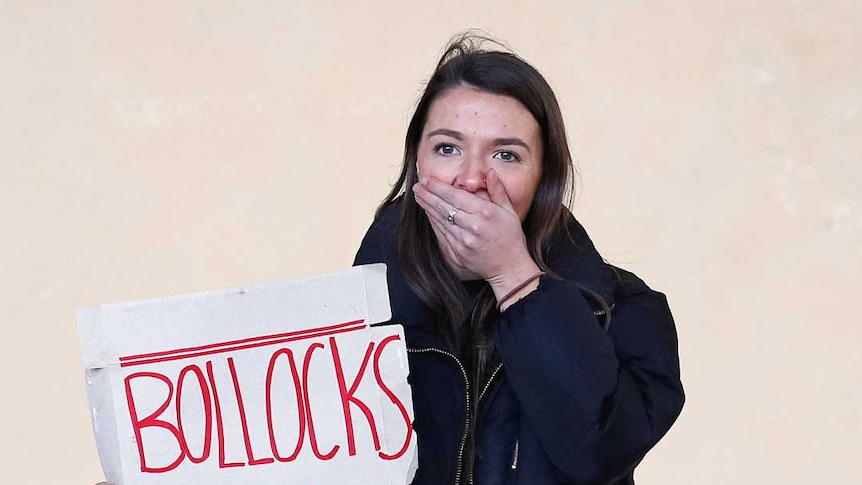 A woman holds a hand over her mouth while hiding a sign that reads Bollocks to Brexit
