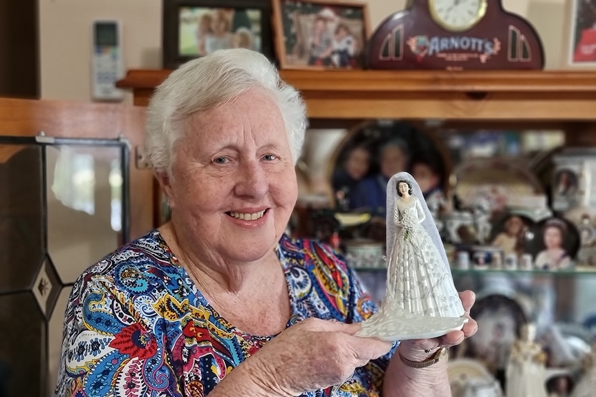 Helen Trustum holding up a figurine of the Queen on her wedding day.