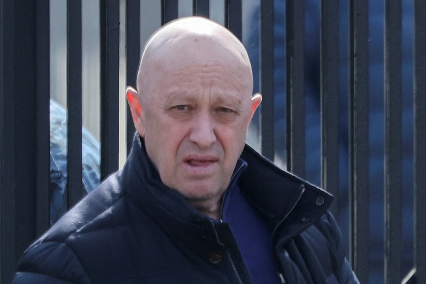 Yevgeny Prigozhin leaves a cemetery. He is bald and stares at the camera from a distance.