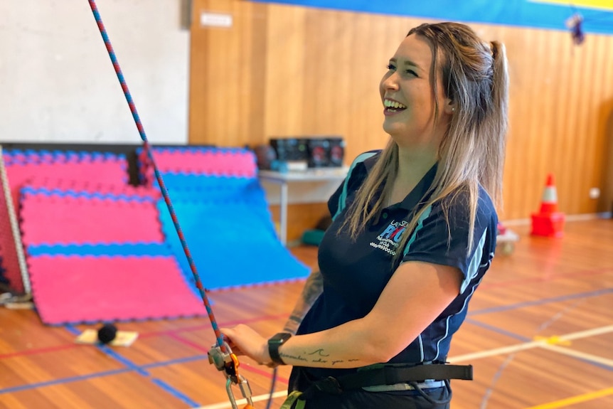 A young woman holds on to abseiling ropes