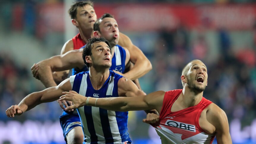 Robbie Tarrant in a blue and white striped singlet grabs a handful of Sam Reid's red and white jersey