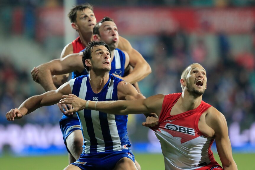 Robbie Tarrant in a blue and white striped singlet grabs a handful of Sam Reid's red and white jersey