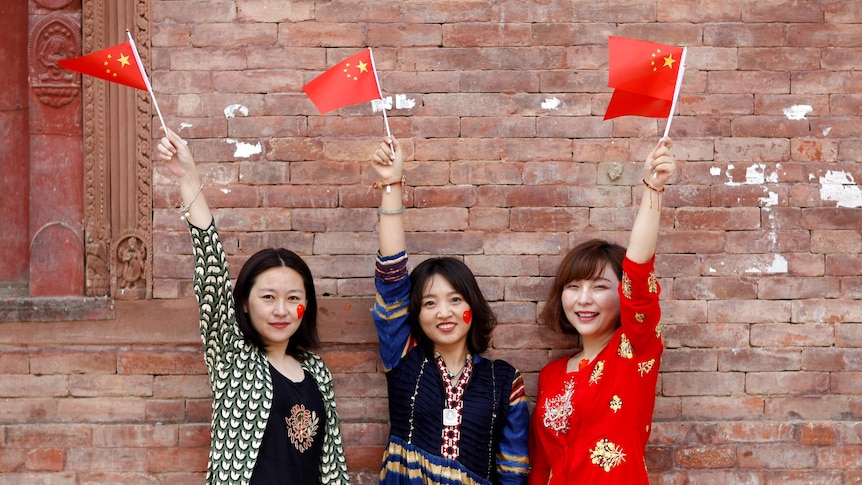 Women holding Chinese flags pose during celebrations to mark the 70th founding anniversary of People's Republic of China