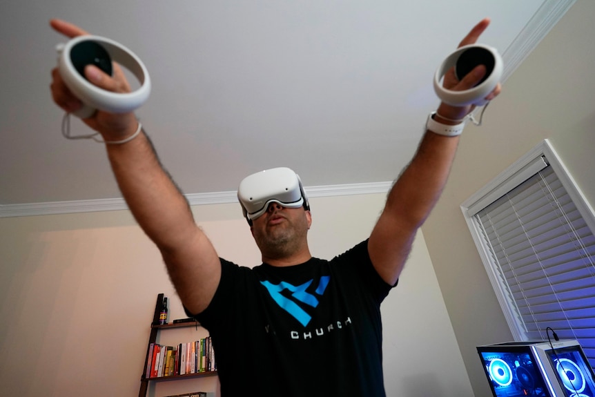 A man in a VR headset with his hands in the air.