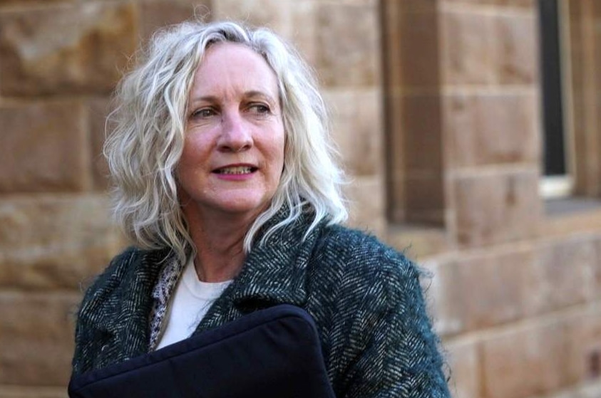 A woman in a thick grey overcoat stands outside court.