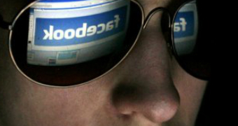 A youth looks at a computer with Facebook logo on it.