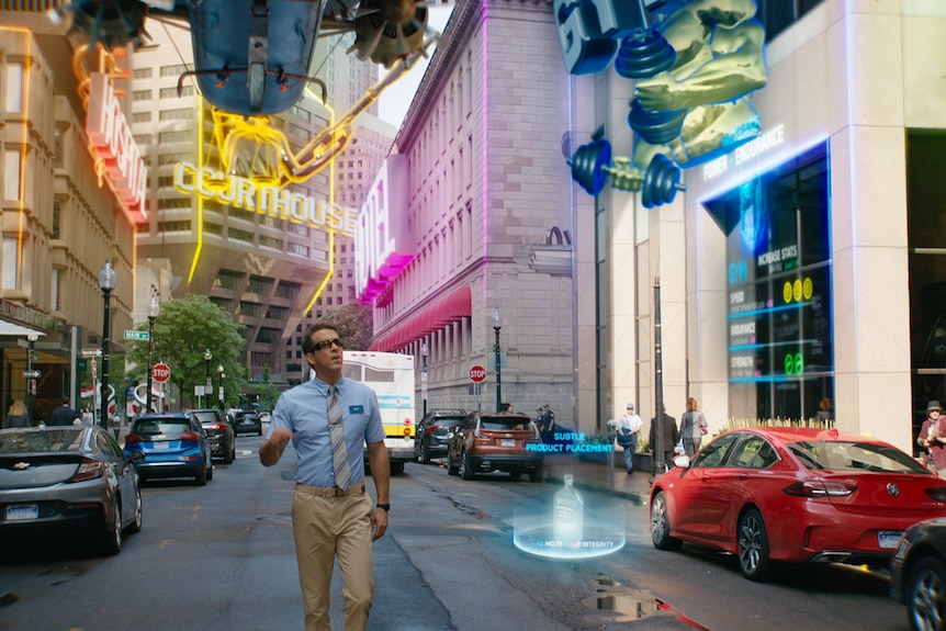 Film still from Free Guy (2021) showing Ryan Reynolds roaming a street lit by bright cosmic lights.