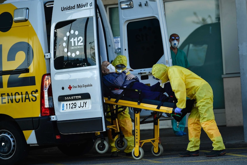 Medical staff wearing special suits arrive with a patient at a Spanish hospital.