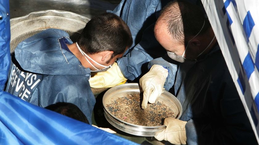 Police officers conduct a forensic archaeological excavation