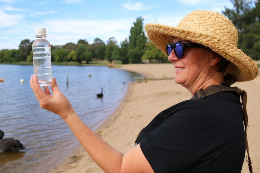 An employee from the National Capital Authority inspects a water sample taken from Lake Burley Griffin.