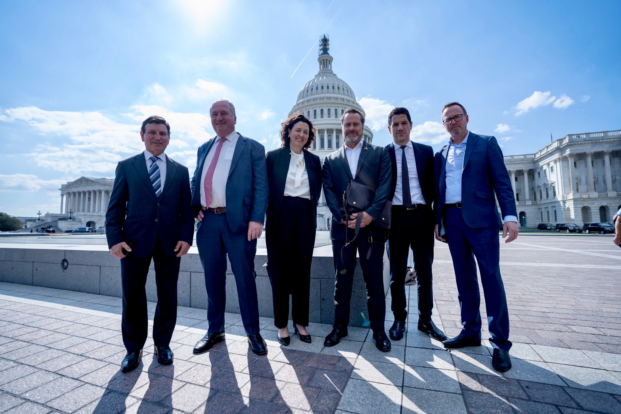 The six politicians stand in front of the US Capitol building.