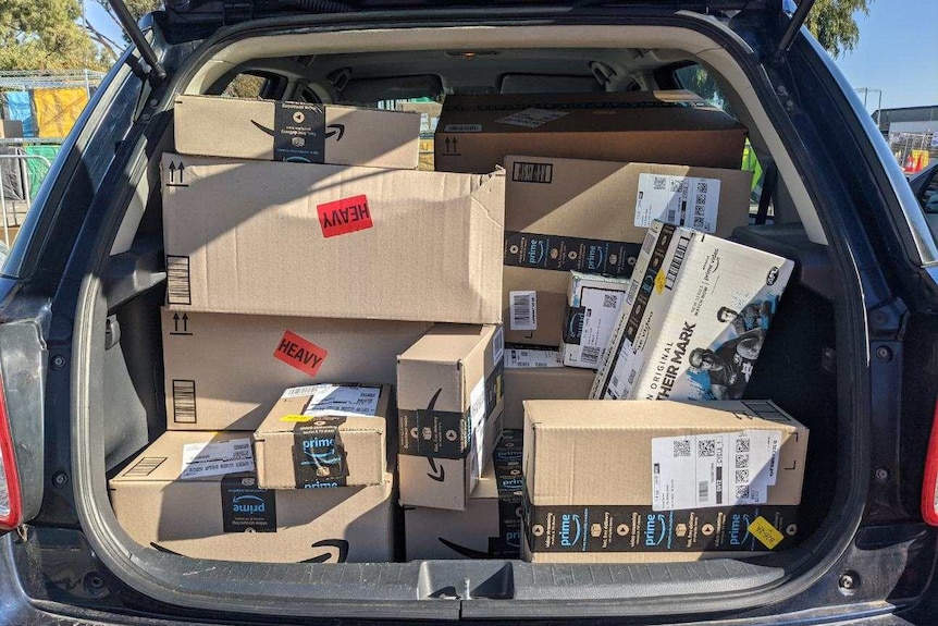 Boxes are stacked to the roof in the boot of a car, blocking the driver's view out the rear.