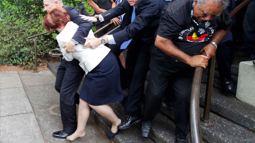 Police and bodyguards escort Julia Gillard and Tony Abbott