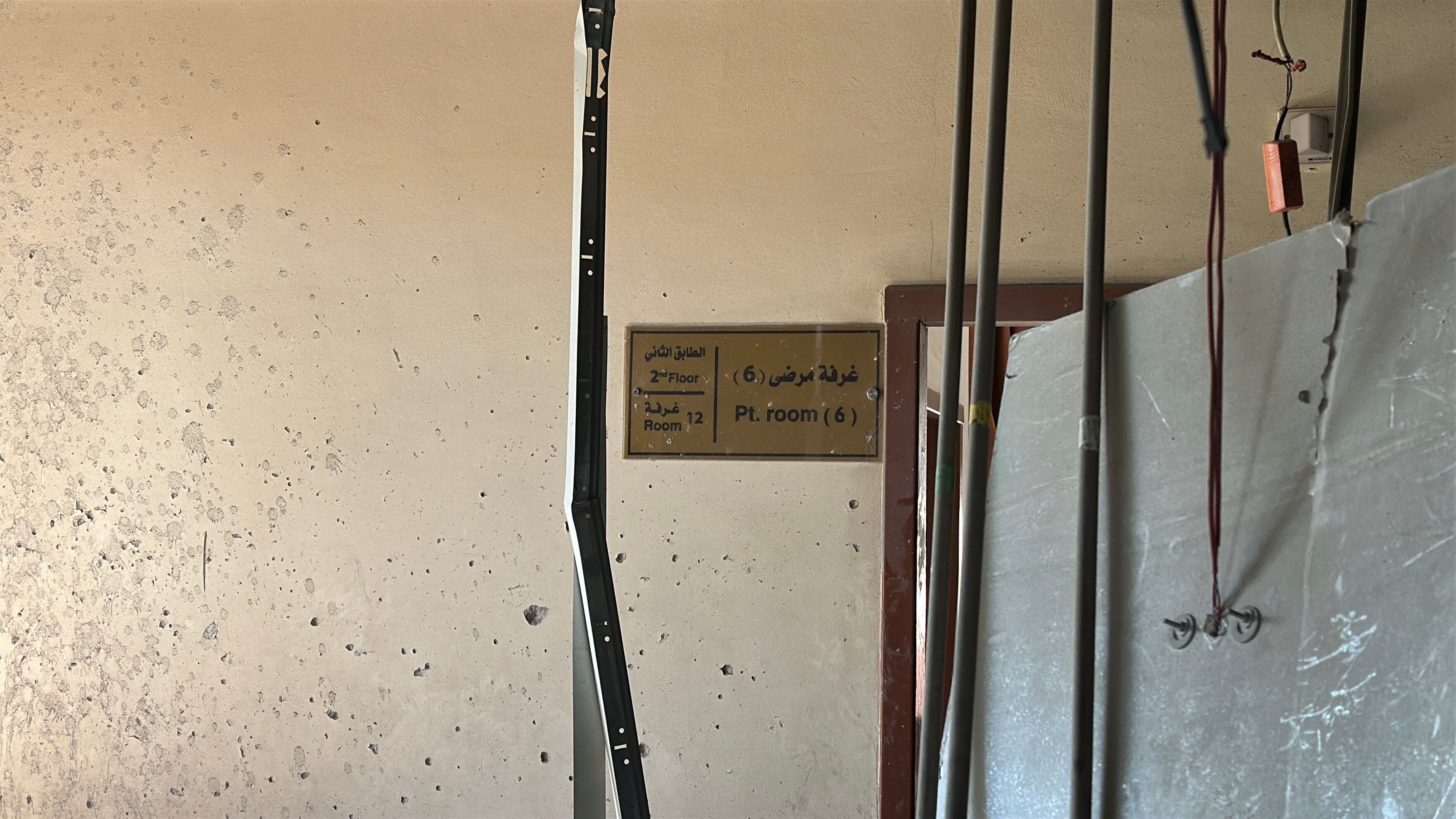 A sign on the wall in Arabic and English says 2nd Floor Room 12 Room 6