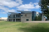 A school building with the words Cedar College written on it next to a grass oval