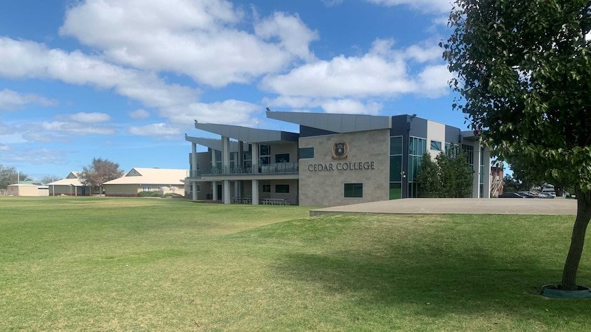 A school building with the words Cedar College written on it next to a grass oval