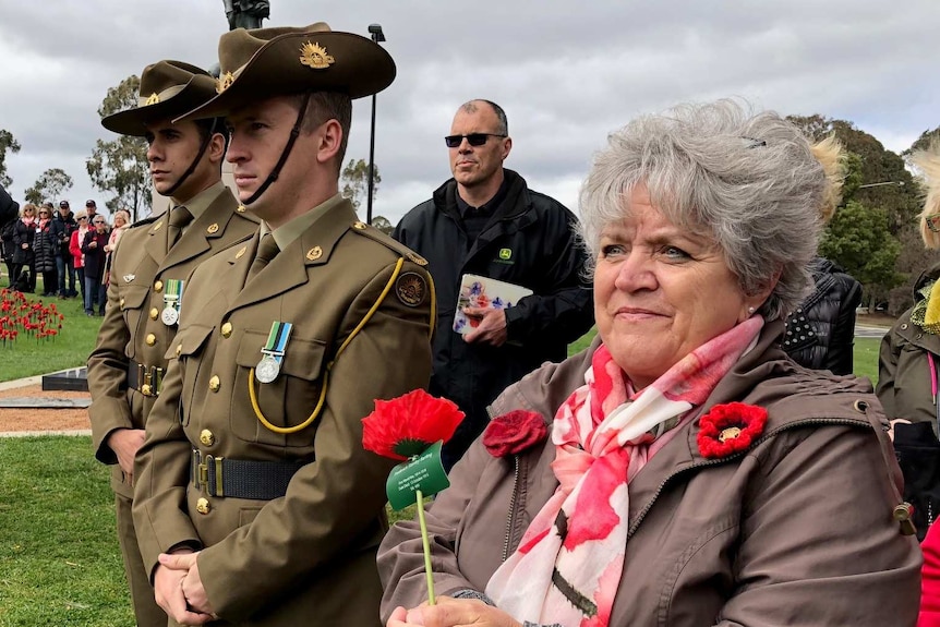 Two soldiers stand among onlookers on the lawn at the Australian War memorial.