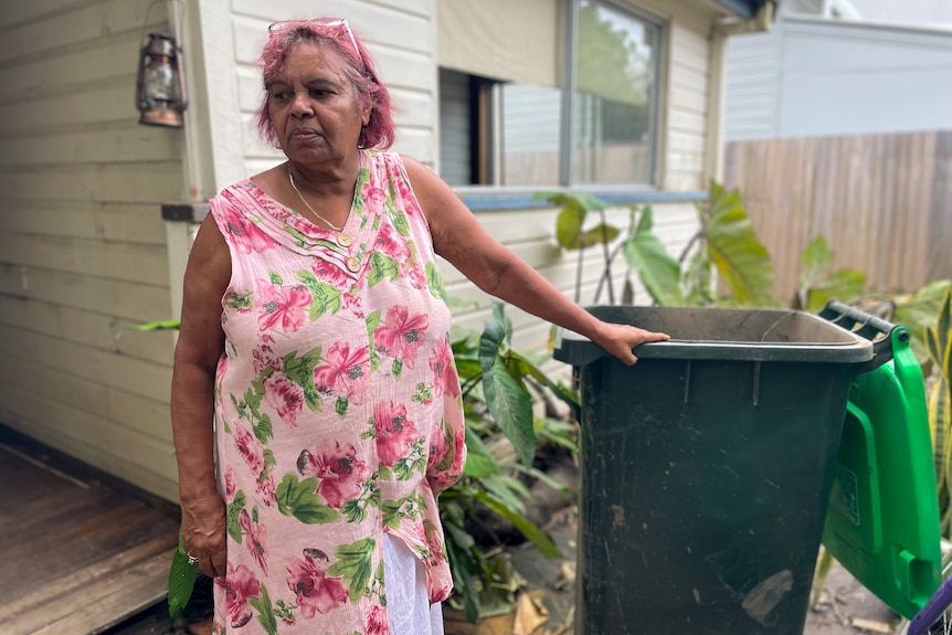 a woman standing next to a garbage bin outdoors