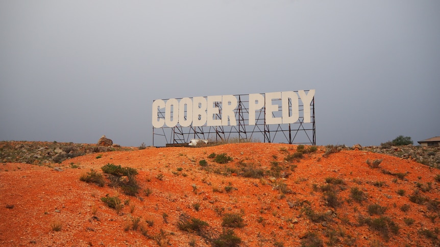 A sign saying "Coober Pedy", similar to the Hollywood sign.
