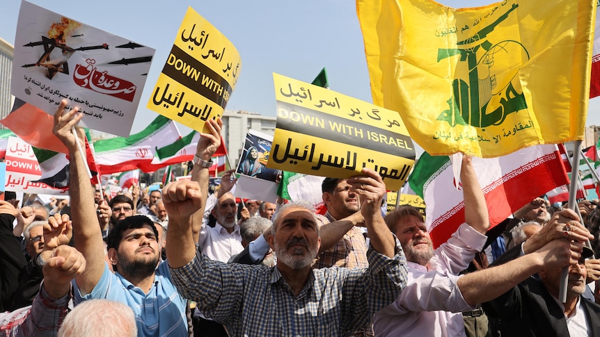 People hold signs that say 'down with Israel' at a protest rally