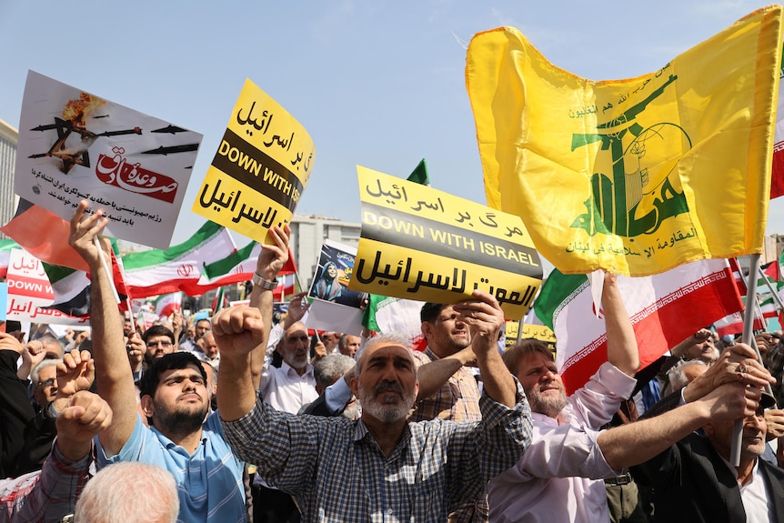 People hold signs that say 'down with Israel' at a protest rally