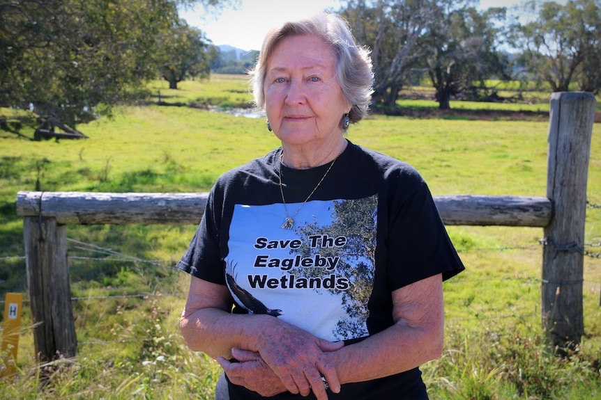 Marilyn Goodwin standing in front of a wooden fence and an open paddock