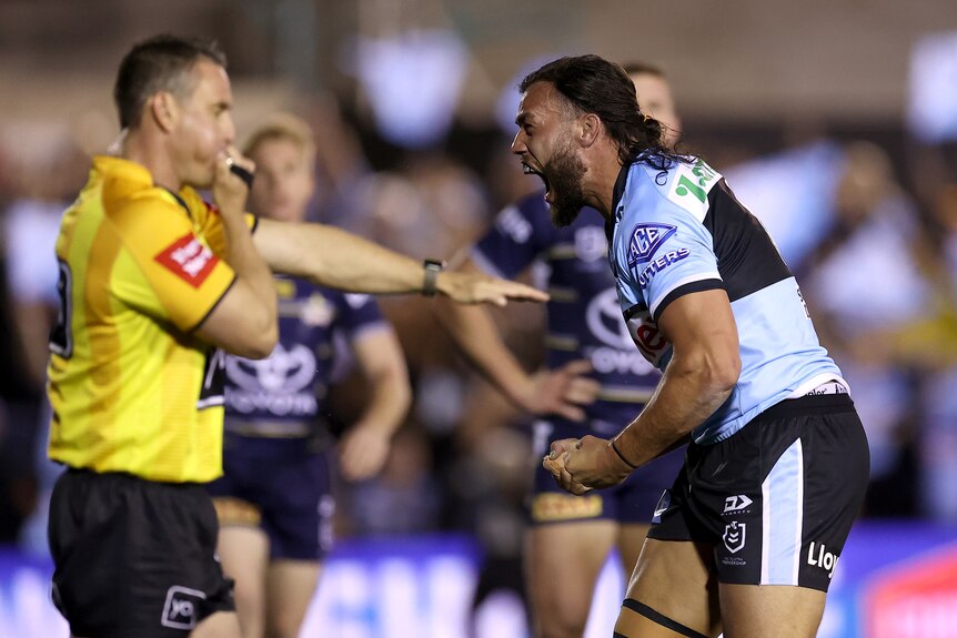 A Cronulla NRL player celebrates as a referee signals a try.